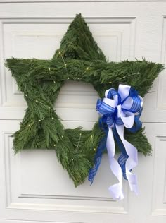 a wreath with blue and white bows hanging on the front door for hanukkah