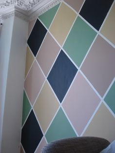 a room that has a wall with different colored tiles on it and a chair in front of the wall