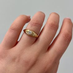 a person's hand with a gold ring on it and a diamond in the middle