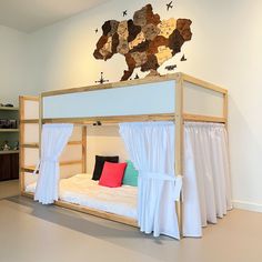 a bunk bed with curtains on the sides and a curtained canopy over it in front of a book shelf