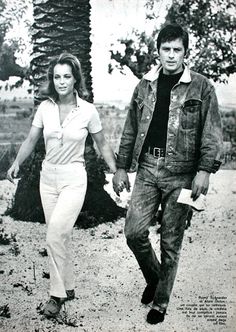 an old black and white photo of a man and woman walking down a dirt road