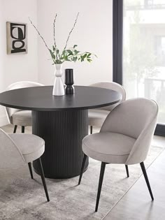 a dining room table with four chairs and a vase filled with flowers on top of it