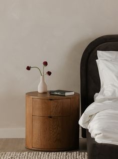 a bedroom with a bed, nightstand and flower vase