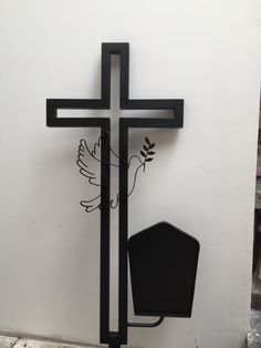 a metal cross with a bird on it next to a trash can and garbage can