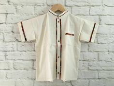 Boy's Traditional Handmade Mexican Guayabera Shirt - Beige - Off White Handmade in Chiapas, Mexico The embroidery pattern & embroidery colors will vary due to the handmade nature of the shirt. If you have any questions or requests please send us a message. Size 2 Measurements (approximate): Length: 12.5 - 13.5 inches Armpit to armpit: 10 - 10.5 inches Size 4 Measurements (approximate): Length: 13.5 - 14 inches Armpit to armpit: 11.5 - 12.5 inches Size 6 Measurements (approximate): Length: 15 - 1 Traditional Cotton Top With Stand Collar, Traditional White Short Sleeve Sets, Traditional Summer Shirt With Camp Collar, Traditional Beige Short Sleeve Tops, Traditional Short Sleeve Cotton Kurta, Traditional Summer Kurta With Woven Motifs, Traditional Cotton Kurta With Short Sleeves, Traditional White Sets With Stand Collar, Fitted Traditional Collared Shirt