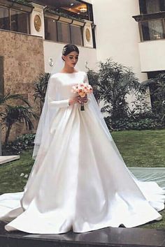 a woman in a white wedding dress standing outside