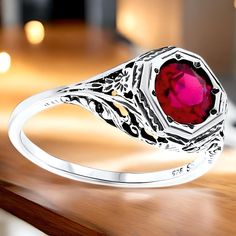 Introducing our stunning Vintage Estate 2.00 Carat Vivid Red Lab-Created Ruby Solitaire Filigree Ring--a true statement piece that combines elegance and artistry. This exquisite ring features a high-quality 6.5 mm lab-created ruby, beautifully set in a 925 solid sterling silver band adorned with delicate floral designs. The top of the ring measures 3/8 inches in length, making it a perfect fit for those who appreciate subtle yet eye-catching jewelry. The vivid red ruby symbolizes love and passion, making it an ideal choice for engagements, anniversaries, or simply to elevate your jewelry collection. To care for your vintage ring, we recommend gently wiping it with a soft, dry cloth after each wear to maintain its shine. Avoid exposing it to harsh chemicals or abrasive surfaces to prevent d Classic Ruby Ring For Valentine's Day, Valentine's Day Classic Ruby Ring, Ruby Filigree Wedding Ring, Red Ruby Filigree Ring For Wedding, Classic Silver Ruby Ring For Valentine's Day, Red Victorian Filigree Ring For Anniversary, Elegant Silver Ruby Ring For Valentine's Day, Classic Red Rings For Valentine's Day, Classic Red Sterling Silver Birthstone Ring