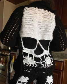 the back of a woman's sweater with crocheted skulls and bones on it