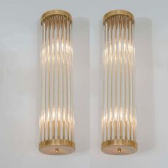 two wall lights that are made out of metal and glass with gold trimmings