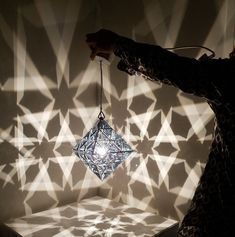 a person holding a light bulb in front of a wall with geometric designs on it