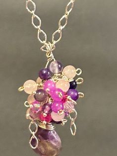 This is a beautiful Handmade one of kind Cluster Pendant Necklace. Made out of beautiful Amethyst, Rose Quartz, Red Purple Jade, Purple Jade, and Rose Chalcedony gemstones.  Hanging by a sterling silver chain closing with a lobster clasp. Measuring at a total 18 inches. Pink Wire Wrapped Crystal Pendant Necklace, Pink Spiritual Crystal Necklaces, Handmade Pink Crystal Necklaces For Party, Handmade Pink Crystal Necklace For Party, Unique Handmade Pink Crystal Necklaces, Handmade Pink Crystal Necklaces, Handmade Pink Round Crystal Necklaces, Unique Pink Gemstone Necklace, Handmade Pink Crystal Round Necklaces