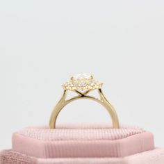 an engagement ring sitting on top of a pink cloth