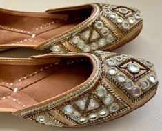 Add a vintage spark to your casual attire with our 'GLITTER GOLD' juttis. A little bit of beads and a little bit of mirrors. WEDDING AND FESTIVE pair of shoes to solve all your wardrobe woes and create a mark wherever you go :) SPECIFICATIONS: *Upper/Panna -Gold fabric base embellished with mirror, gold beads, pipes and zari work. *Back/Adda - Gold fabric base embellished with mirror, gold beads, pipes and zari work. *Lining - Leather *Padding - Double Cushioning for extra comfort *Sole/Talla - Festive Mirror Work Slip-on Flats, Traditional Flats With Mirror Work For Navratri, Festive Diwali Closed Toe Flats, Festive Closed Toe Flats For Diwali, Festive Bollywood Flats With Gota Work, Festive Mirror Work Closed Toe Flats, Bollywood Style Festive Flats With Gota Work, Bollywood Flats With Zari Work For Diwali, Festive Gota Work Closed Toe Flats