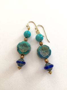 "Lightweight earrings handmade of semi-transparent aqua blue Czech glass Picasso flower, 8mm turquoise howlite, and cobalt blue Picasso UFO bead. Accented with light bronze Czech glass beads and gold wire. Earrings come on simple gold plated fish hook ear wires, lead and nickel free. Measure 2 1/8\"'long from top of ear wire." Artisan Blue Beaded Round Earrings, Blue Round Beaded Earrings With Spacer Beads, Turquoise Glass Earrings For Gift, Blue Flower Earrings Nickel Free, Blue Round Beaded Earrings As Gift, Turquoise Czech Glass Round Jewelry, Blue Beaded Earrings For Gifts, Blue Round Beaded Earrings For Gift, Blue Flower-shaped Jewelry For The Beach