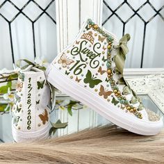 a pair of white high top sneakers with green and gold butterflies on them, sitting next to each other