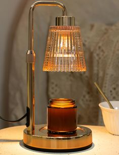 a table lamp sitting on top of a wooden table next to a bowl and cup