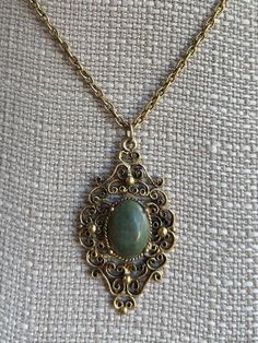 Vintage Victorian Revival Bronze Nephrite Medallion Filigree Necklace 18" Item here is a vintage Victorian Revival bronze filigree medallion necklace with a nephrite stone. This necklace opens and closes with a spring ring clasp. Very neat Victorian design with a lovely green jade stone.  Condition: Great; item is pre-owned and may have some signs of light use and age related wear. Please look closely at the pictures provided as they are an extension of our written description. Measurements: Length: 18 in Chain Width: 3mm Pendant: 2 ⅛ in x 1 ¼ in Weight: 14.8 g 4589C Luxury Vintage Engraved Medallion Necklace, Vintage Filigree Round Pendant Necklace, Bronze Filigree Pendant Necklace, Vintage Filigree Necklace With Round Pendant, Bronze Filigree Metal Necklace, Bronze Metal Necklace With Filigree, Antique Gold Nickel-free Medallion Necklace, Vintage Necklace With Round Antique Pendant, Vintage Antique Gold Necklace With Intricate Design