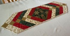 a quilted table runner sitting on top of a white bed next to a wooden headboard