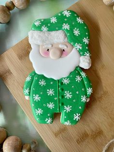 a green and white santa clause cookie sitting on top of a cutting board next to garlic