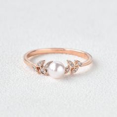 a pearl and diamond ring on a white surface