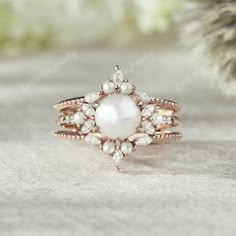 a white pearl and diamond ring on top of a pine tree branch in the snow