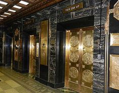 the elevators are decorated with gold and black marble panels, along with decorative wall art