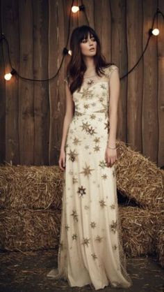 a woman standing in front of hay bales wearing a dress with flowers on it