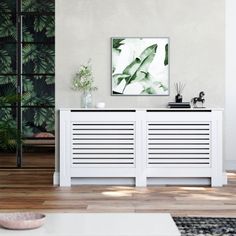 a living room with two white sideboards and a painting on the wall behind them