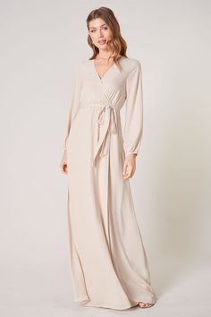 Warm and inviting, the Wholehearted Maxi Dress is a perfect combination of modest and sultry. Long balloon sleeves frame a surplice neckline separated by a tie at the waist, creating a forgiving faux wrap. The skirt maintains an airy and flowy shape that trails behind as you walk down the aisle. - Chiffon- Faux wrap- Keyhole- Elastic waist- Comes in 14 ColorsSize + Fit - Model is 5'9" and wearing size XS- Measurements taken from size S - Chest: 35"- Length: 63 1/4" Fabric Self: 100% PolyesterLin Taupe Dress, Fashion Ads, Wrap Maxi Dress, Long Bridesmaid Dress, Walk Down The Aisle, Maxi Dress Wedding, Backless Maxi Dresses, Surplice Neckline, Flowing Skirt