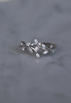 a close up of a ring with leaves on the front and back, sitting on a table