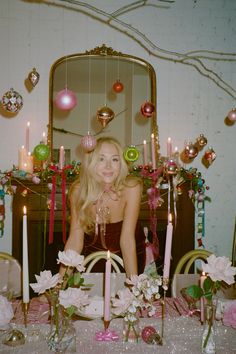 a woman sitting in front of a table with candles and decorations on top of it