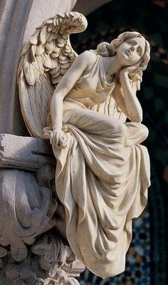 an angel statue sitting on top of a pillar