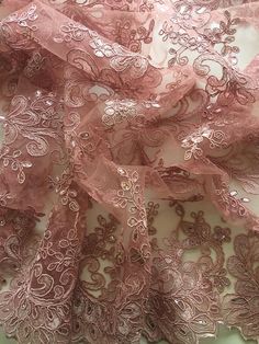 an image of pink lace fabric with flowers on the bottom and center, as seen from above