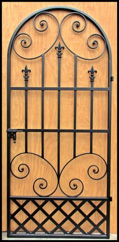 an iron gate is shown against a wooden wall and has scroll designs on the sides