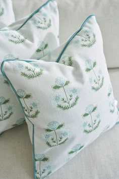 two pillows sitting on top of a couch next to each other with green plants printed on them