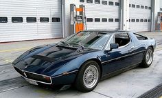 a blue sports car parked in front of two garage doors