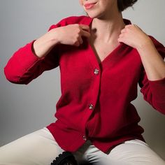 The Rosie cardigan in red is a vibrant and cozy garment that effortlessly combines comfort with style. This piece is  made of luxury cotton piqué imported from Italy. The rich red hue adds a pop of color, making it a versatile piece that can elevate both casual and semi-formal ensembles.  Adding a touch of elegance and sophistication, the cardigan features an embroidered logo on the back and under the collar, and includes silver buttons with shield motif that run down the front, providing a polished and timeless aesthetic.   Whether worn open or buttoned up, this cotton red cardigan is a versatile and stylish wardrobe staple.  93% Cotton, 7% Polyamide Wash Max 30º Do not use bleach Iron Max 150º Dry cleaning Do not use dryer Dry on horizontal surface Red Cotton V-neck Cardigan, Elegant Red V-neck Cardigan, Classic Red Fitted Cardigan, Classic Red Sweater For Fall, Classic Fitted Red Cardigan, Elegant Red Cardigan For Fall, Classic Red Cotton Cardigan, Elegant Red Winter Cardigan, Build A Wardrobe