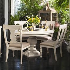 a white table and chairs sitting on top of a wooden floor next to a window