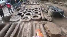 people are standing around in the mud near some tires