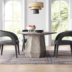 a dining table with chairs around it in front of two windows and an area rug on the floor