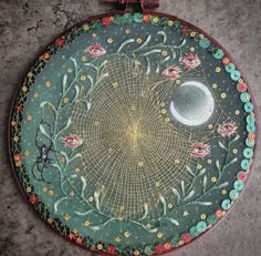 a circular painting on the ground with flowers and a half moon in the sky above it