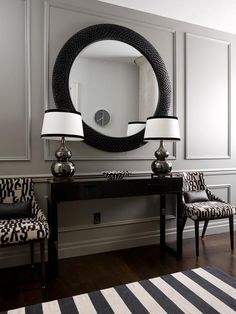 a black and white room with two lamps, a mirror and a table in front of it