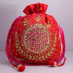 a red bag with gold designs on the front and pink tassels around it