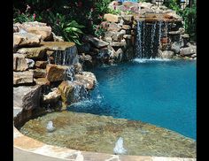 an outdoor pool with waterfall and rocks surrounding it