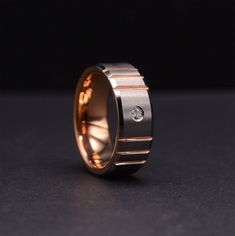 a gold ring with a diamond on the inside and in the outside, sitting on a black surface