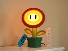 a nintendo wii controller sitting on top of a table next to a lamp that looks like a flower