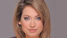 a woman with blonde hair and blue eyes is posing for a headshot in front of a gray background