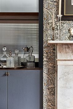 a room with a fireplace and wallpaper on the walls, including an old fashioned cabinet