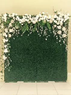 an artificial green wall with white flowers and greenery