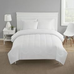 a bed with white sheets and pillows in a bedroom next to a lamp on a table